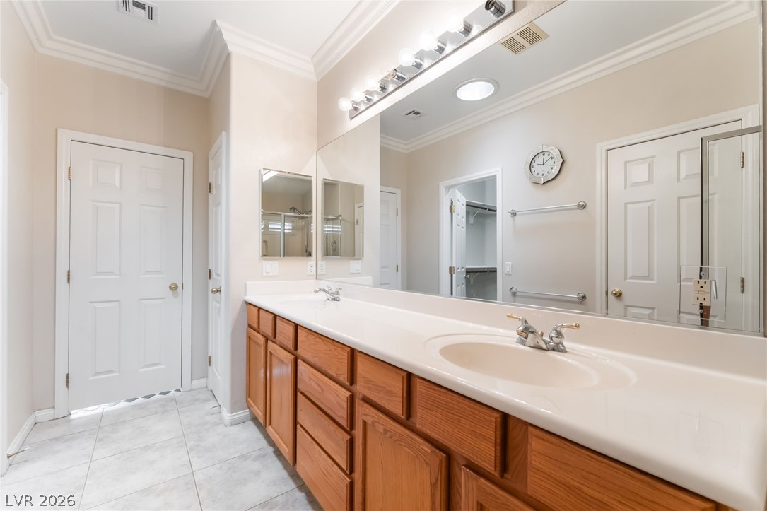 10481 Riverside Park Avenue Las Vegas, NV 89135 - Photo 22 of 51 Bathroom featuring double vanity, crown molding, and light tile patterned floors