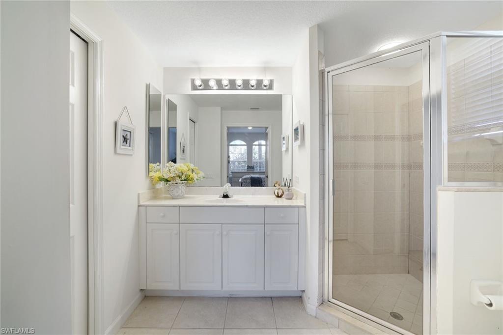 10049 Heather Lane, Unit 101 Naples, FL 34119 - Photo 21 of 28 Full bathroom featuring a shower stall, connected bathroom, and light tile patterned flooring