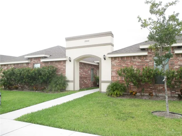 a view of a house with brick walls and a yard with plants
