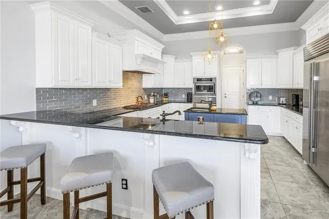 a kitchen with stainless steel appliances granite countertop a sink a stove a refrigerator cabinets and chairs