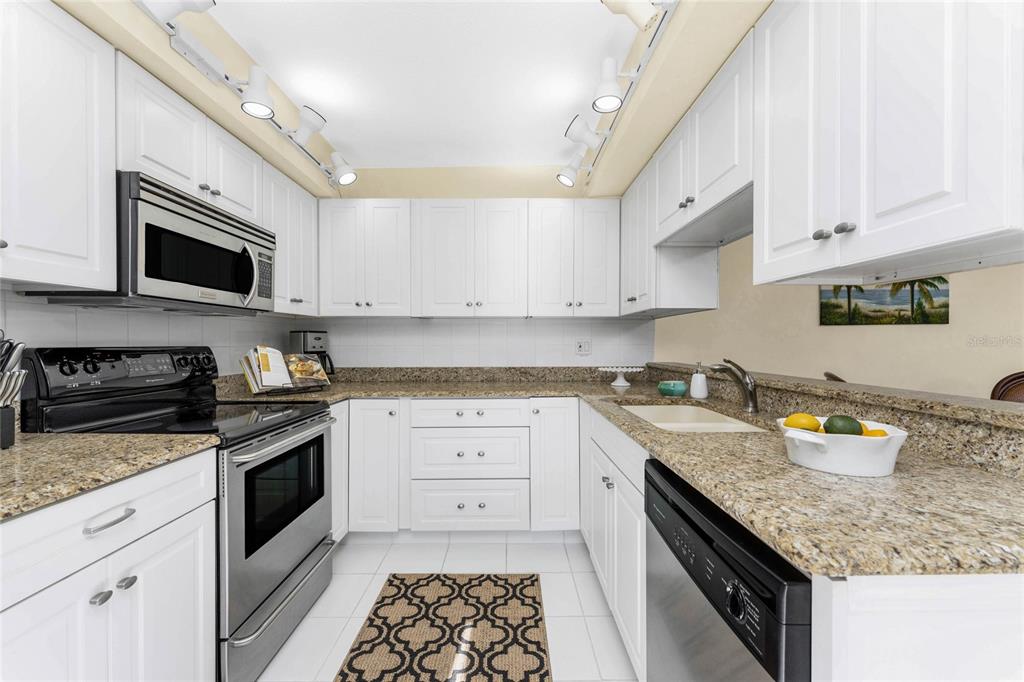 3021 Matecumbe Key Road, Unit 4 Punta Gorda, FL 33955 - Photo 15 of 42 a kitchen with granite countertop stainless steel appliances and white cabinets