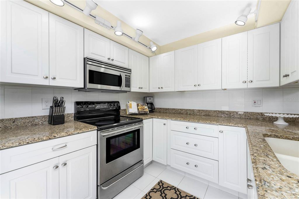 3021 Matecumbe Key Road, Unit 4 Punta Gorda, FL 33955 - Photo 16 of 42 a kitchen with granite countertop white cabinets white stainless steel appliances and a sink