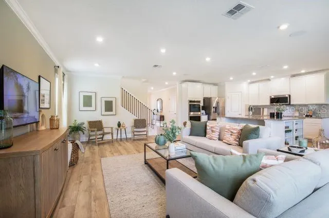 a living room with furniture kitchen view and a large window