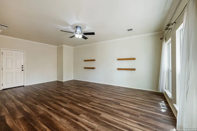 a view of empty room with wooden floor and fan