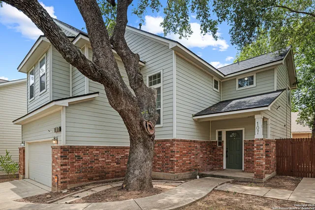 a front view of a house with a tree