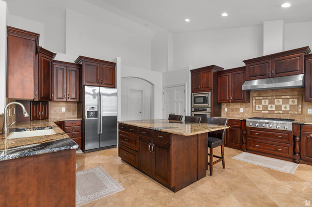 439 East 13540 South Draper, UT 84020 - Photo 8 of 46 Gourmet kitchen featuring rich wood cabinetry, granite countertops, a large center island with seating, stainless steel appliances, and tile flooring