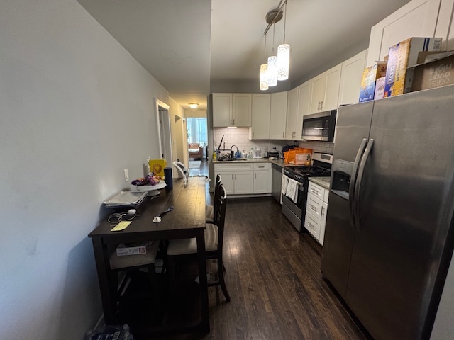 1431 North Springfield Avenue, Unit 2 Chicago, IL 60651 - Photo 11 of 19 a kitchen with stainless steel appliances a dining table chairs and a refrigerator