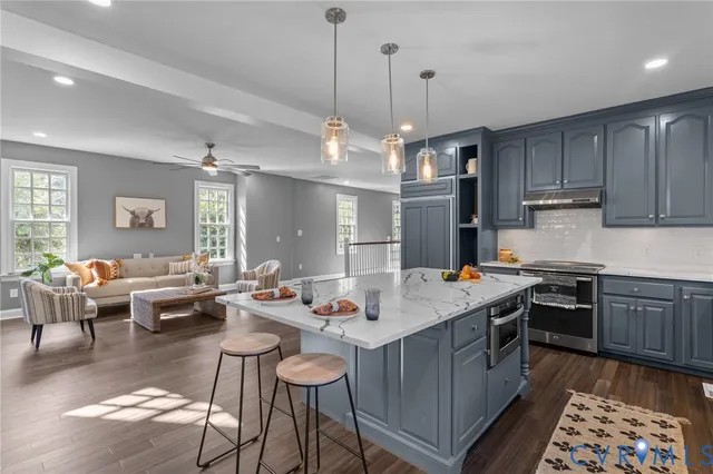 a open kitchen with stainless steel appliances granite countertop a stove top oven a dining table and chairs with wooden floor