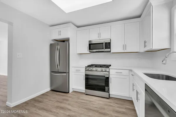 a kitchen with stainless steel appliances granite countertop a refrigerator stove a sink and microwave with wooden floors