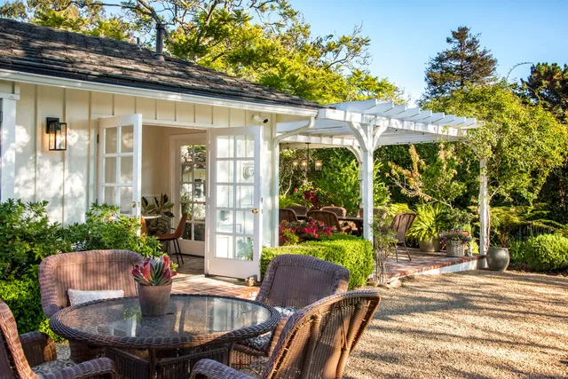 a view of a patio with table and chairs potted plants and floor to ceiling window and potted plants