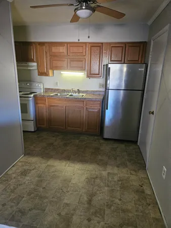 a kitchen with granite countertop a refrigerator a sink a stove a microwave a counter top and cabinets