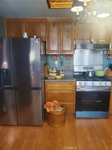 a kitchen with stainless steel appliances granite countertop a refrigerator a stove and a sink with wooden floors