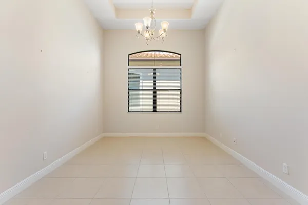 an empty room with windows and chandelier fan