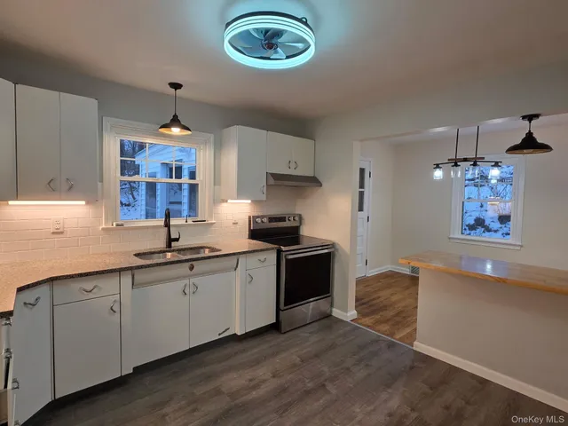 a kitchen with stainless steel appliances granite countertop a sink and a stove with wooden floor