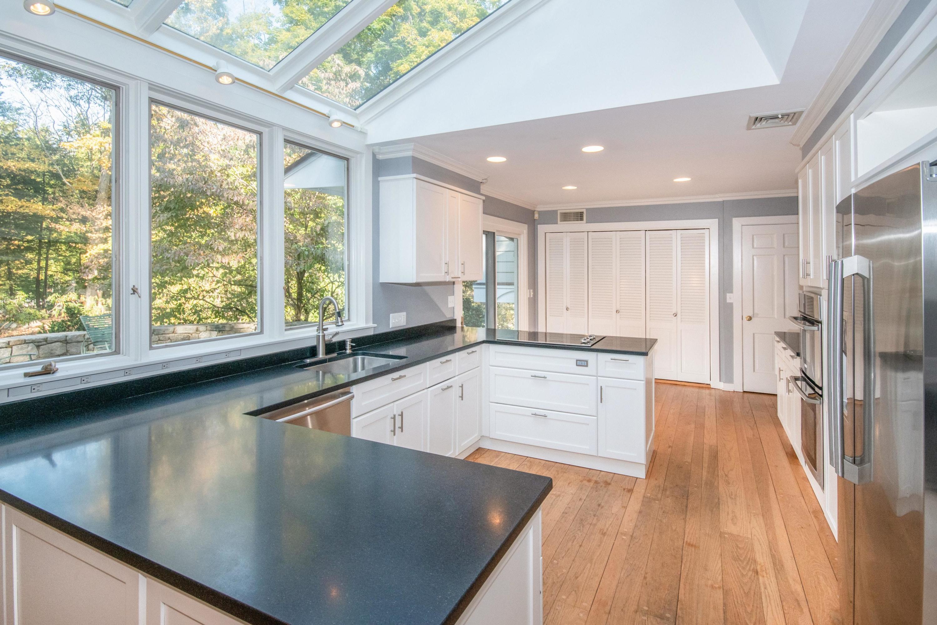 54 Huckleberry Hill Road New Canaan, CT 06840 - Photo 10 of 37 a large kitchen with stainless steel appliances a large counter top a stove a chimney a sink and a large window