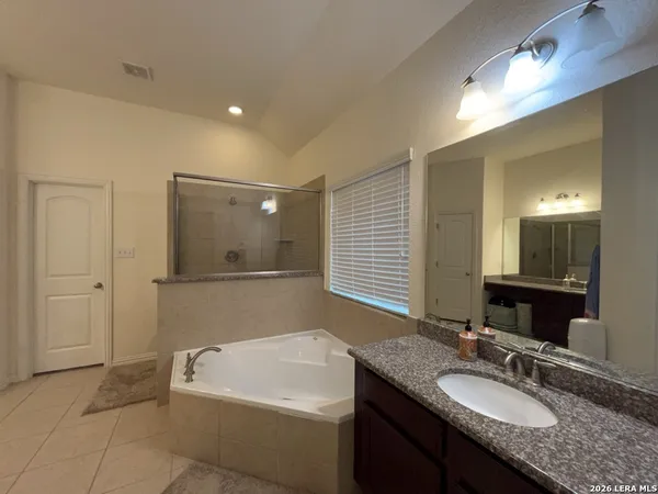 a bathroom with a granite countertop sink a large mirror and a bathtub