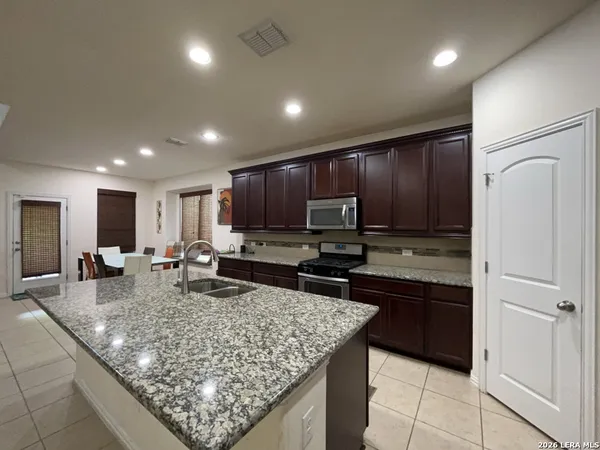 a kitchen with kitchen island granite countertop stainless steel appliances a sink stove and refrigerator