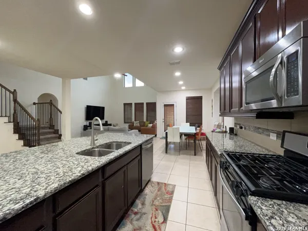 a kitchen with stainless steel appliances granite countertop a sink a stove and a wooden floors