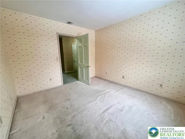 a view of an empty room with wooden floor and stairs