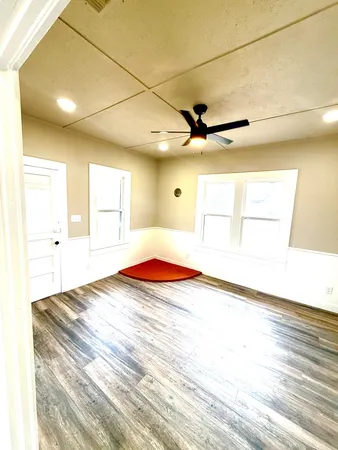a view of a room with a ceiling fan and wooden floor