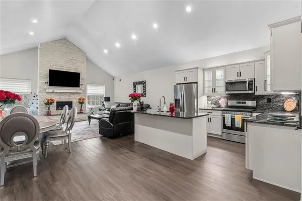 a living room with furniture a flat screen tv and kitchen view