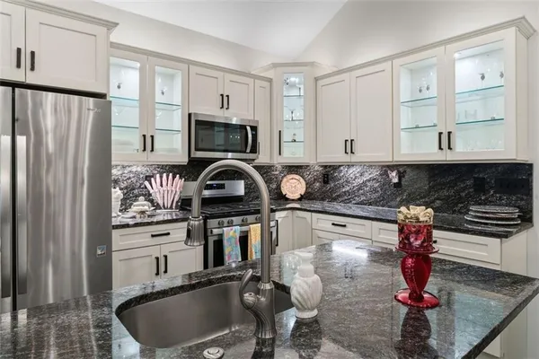 a kitchen with stainless steel appliances granite countertop a sink stove and refrigerator