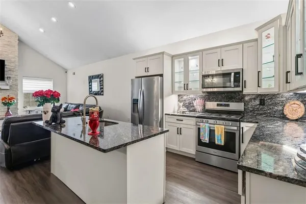a kitchen with stainless steel appliances granite countertop a sink refrigerator and microwave
