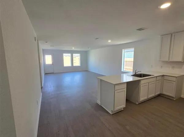 a kitchen with white cabinets and wooden floors