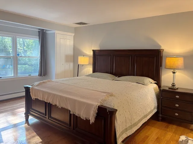 a large bed sitting in a bedroom next to a lamp next to a window