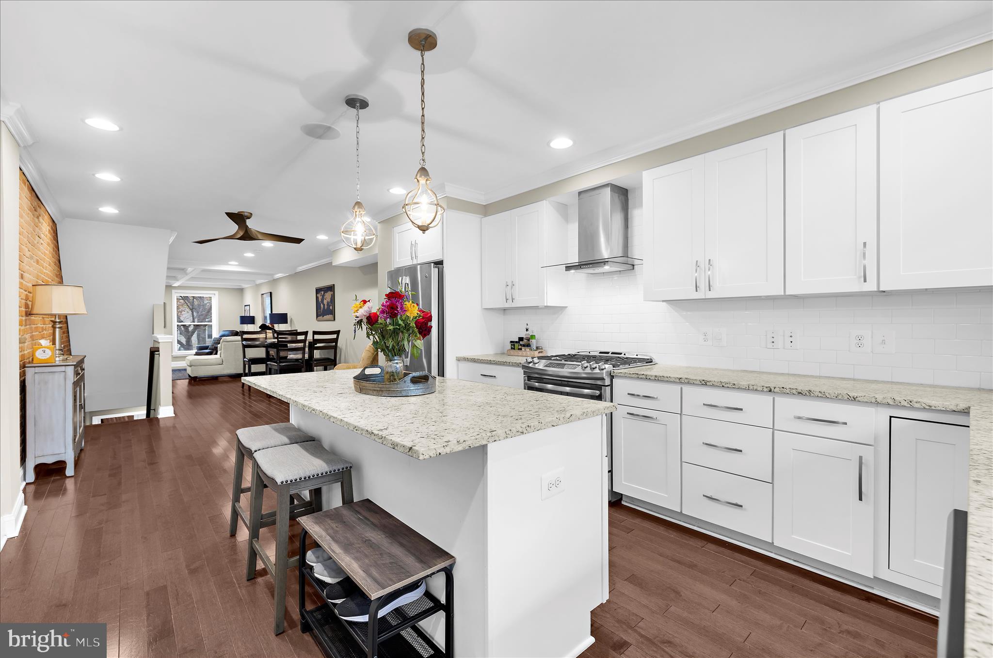 932 South Clinton Street Baltimore, MD 21224 - Photo 11 of 46 a kitchen with stainless steel appliances kitchen island granite countertop a stove a sink a dining table and chairs with wooden floor