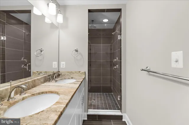 a bathroom with a granite countertop sink a mirror and shower