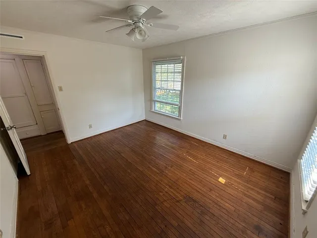 a view of empty room with wooden floor and fan