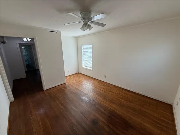 an empty room with wooden floor and a ceiling fan