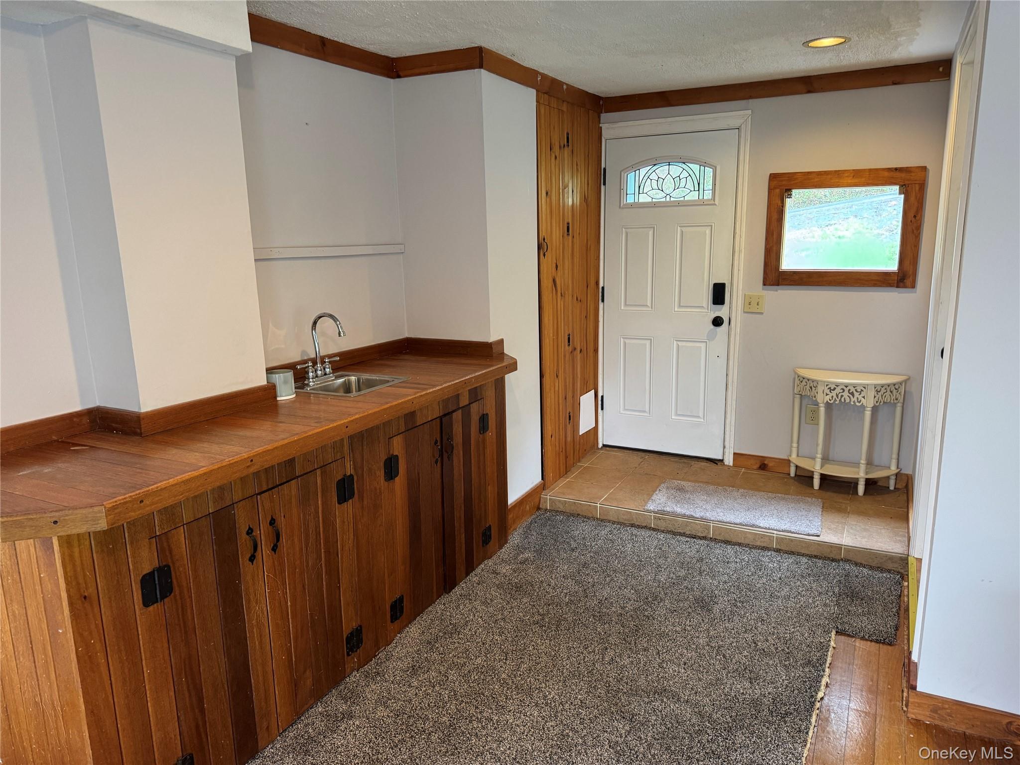 96 White Roe Lake Road Livingston Manor, NY 12758 - Photo 28 of 31 Entry area featuring a wood counter with a wet bar, paneled cabinetry, and a white door with a decorative glass insert