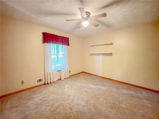 an empty room with a ceiling fan and a window