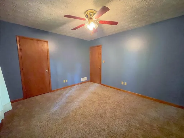 a view of an empty room and chandelier fan