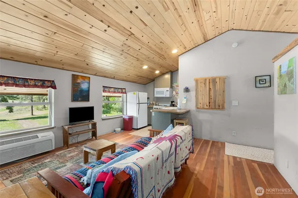 a living room with furniture a flat screen tv and floor to ceiling window
