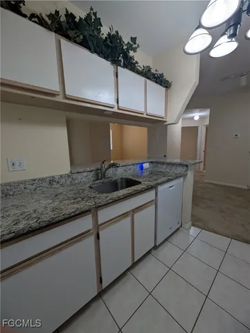 a kitchen with granite countertop a sink and white cabinets