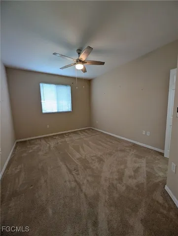 en empty room with windows and chandelier fan