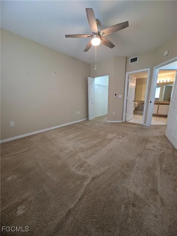 an empty room with chandelier fan and windows