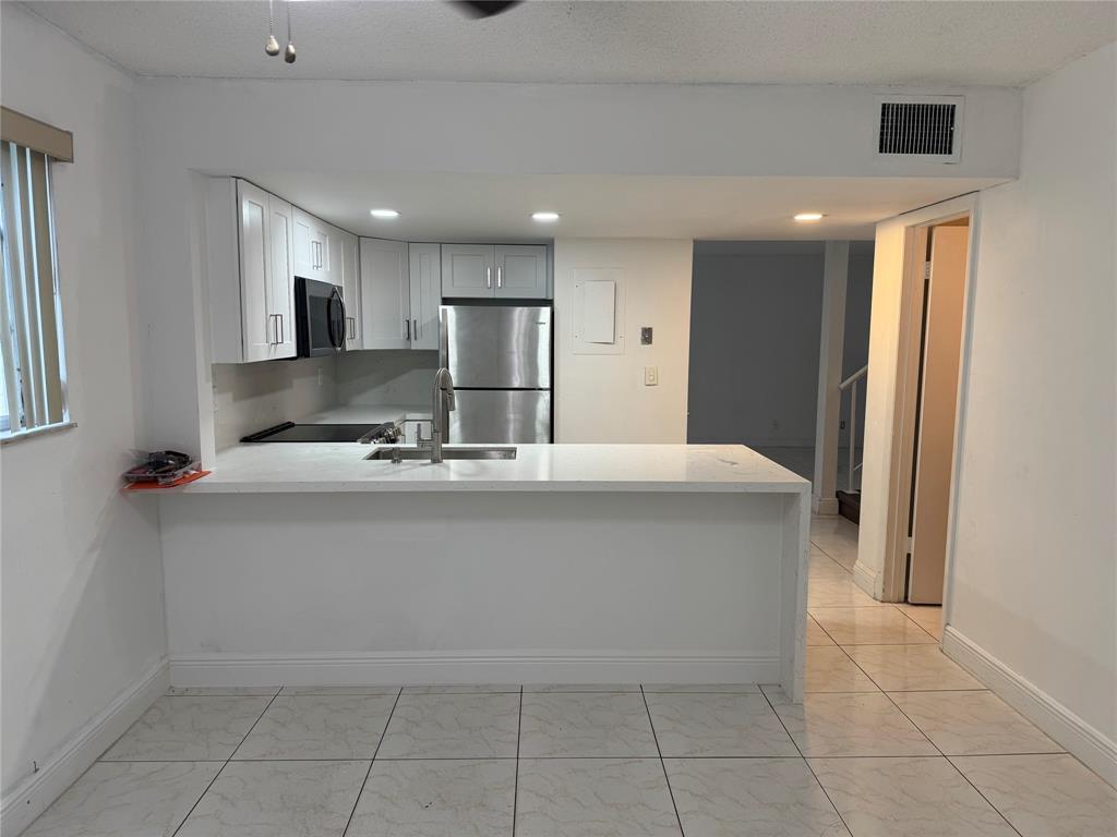 8031 Lagos De Campo Boulevard, Unit L3 Tamarac, FL 33321 - Photo 1 of 26 a large kitchen with kitchen island a sink stainless steel appliances and cabinets