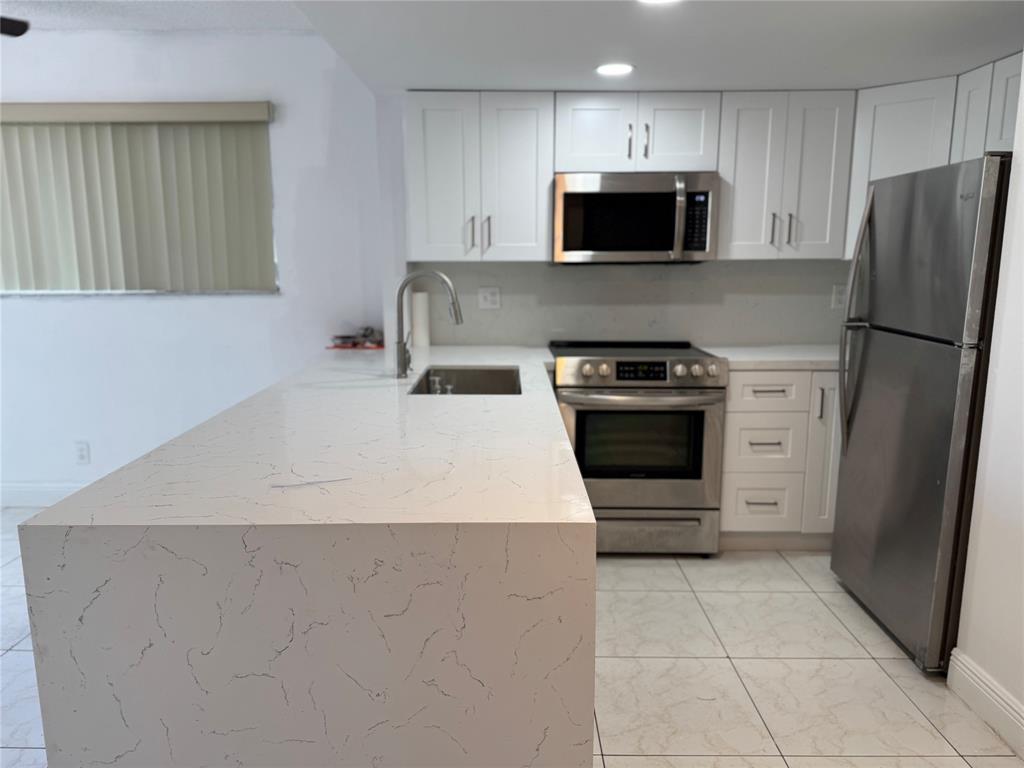 8031 Lagos De Campo Boulevard, Unit L3 Tamarac, FL 33321 - Photo 3 of 26 a kitchen with a stove a microwave and refrigerator