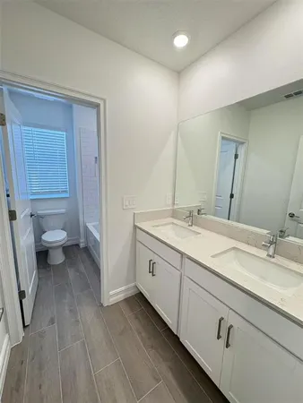 a spacious bathroom with a granite countertop sink toilet and mirror