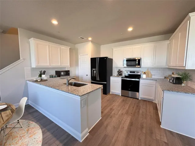a kitchen with kitchen island a stove a sink a refrigerator and cabinets