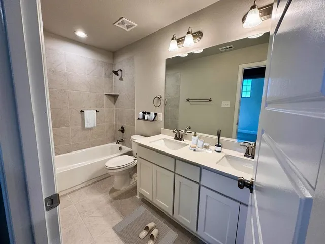 a bathroom with a double vanity sink toilet mirror and bathtub