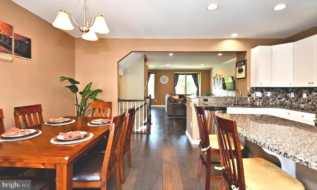 a kitchen with stainless steel appliances granite countertop a stove a sink a dining table and chairs with wooden floor