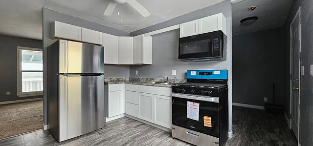 a kitchen with stainless steel appliances granite countertop a stove top oven a sink and a refrigerator