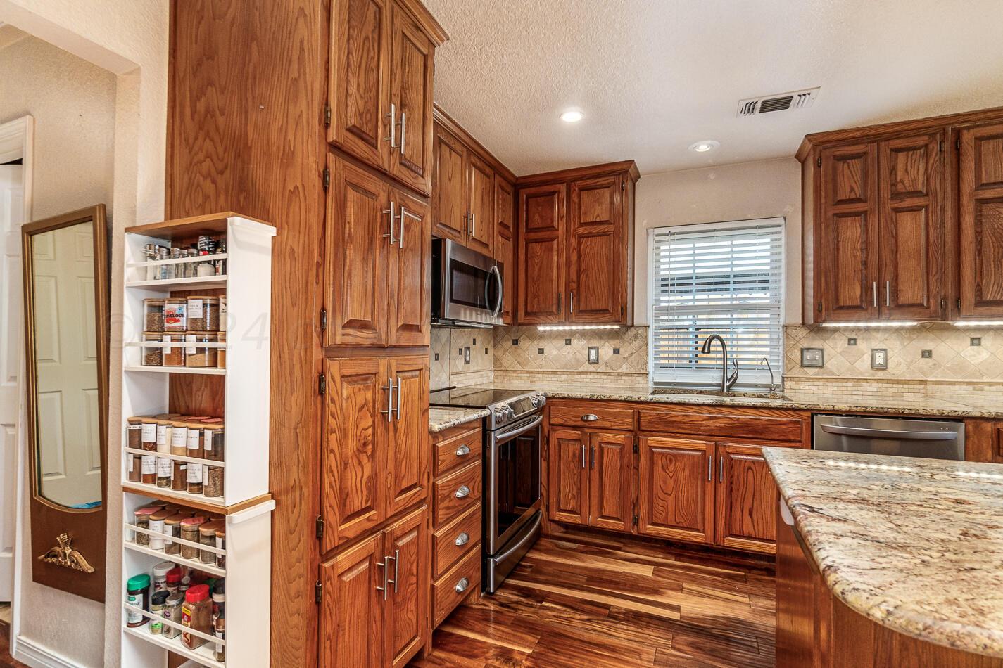 5132 Arden Road Amarillo, TX 79110 - Photo 3 of 28 a kitchen with stainless steel appliances granite countertop a refrigerator and wooden cabinets