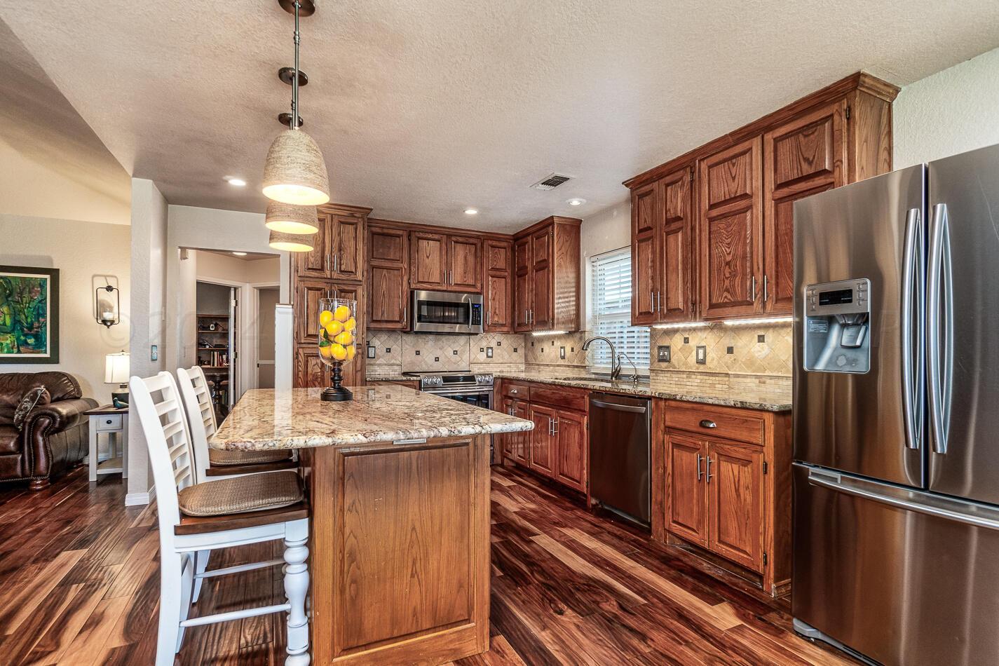 5132 Arden Road Amarillo, TX 79110 - Photo 8 of 28 a kitchen with stainless steel appliances granite countertop a refrigerator a stove a sink dishwasher a dining table and chairs with wooden floor