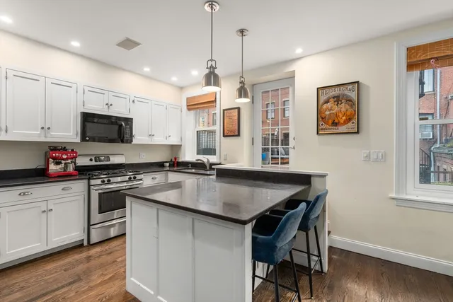 a kitchen with a center island white wooden cabinets and stainless steel appliances